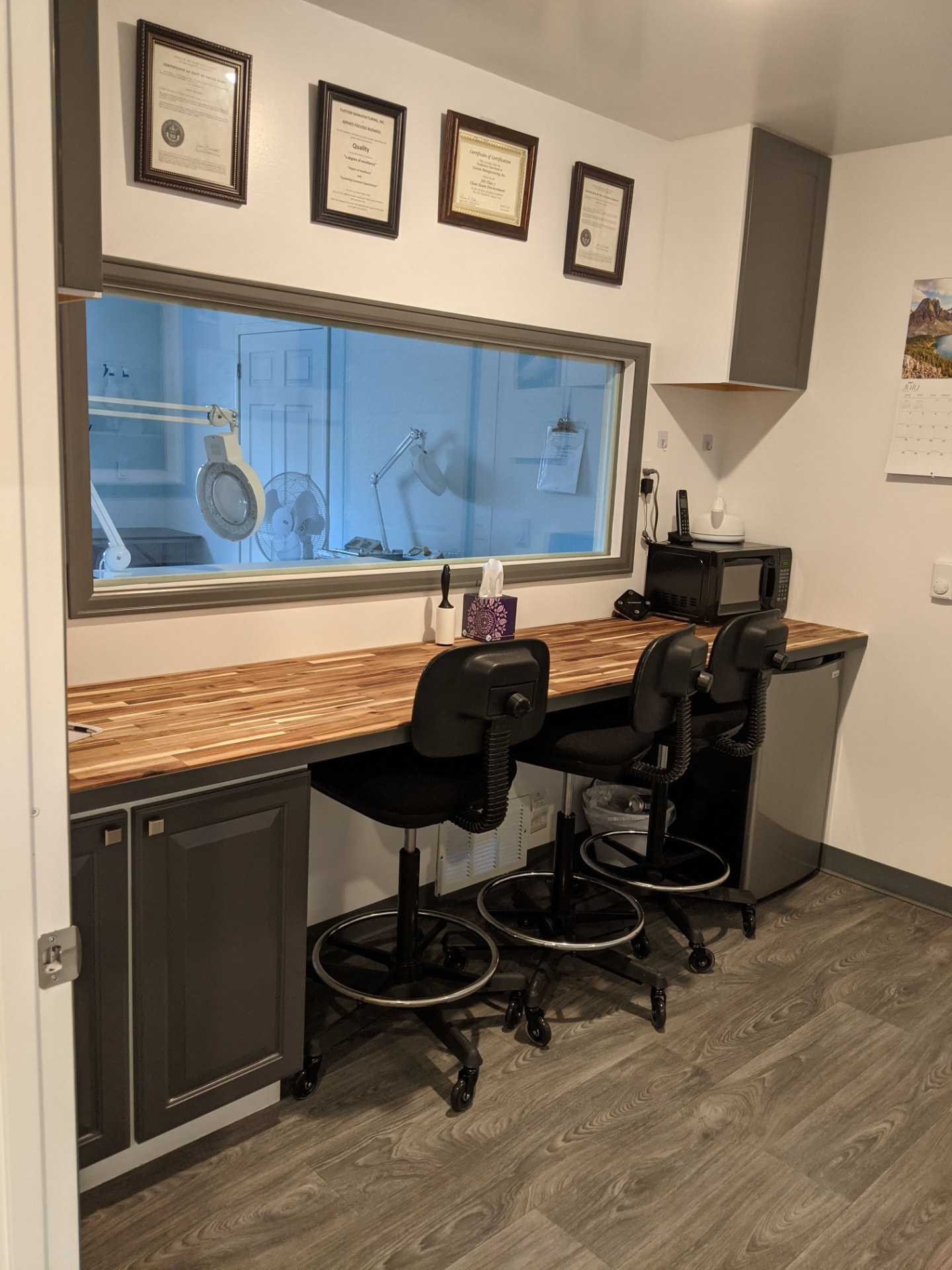CMI office workstation with framed certifications above the cleanroom window